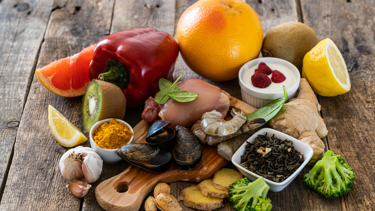 Ostras, ajo, pimiento, yogur, cítricos y otros alimentos sobre una mesa de madera.