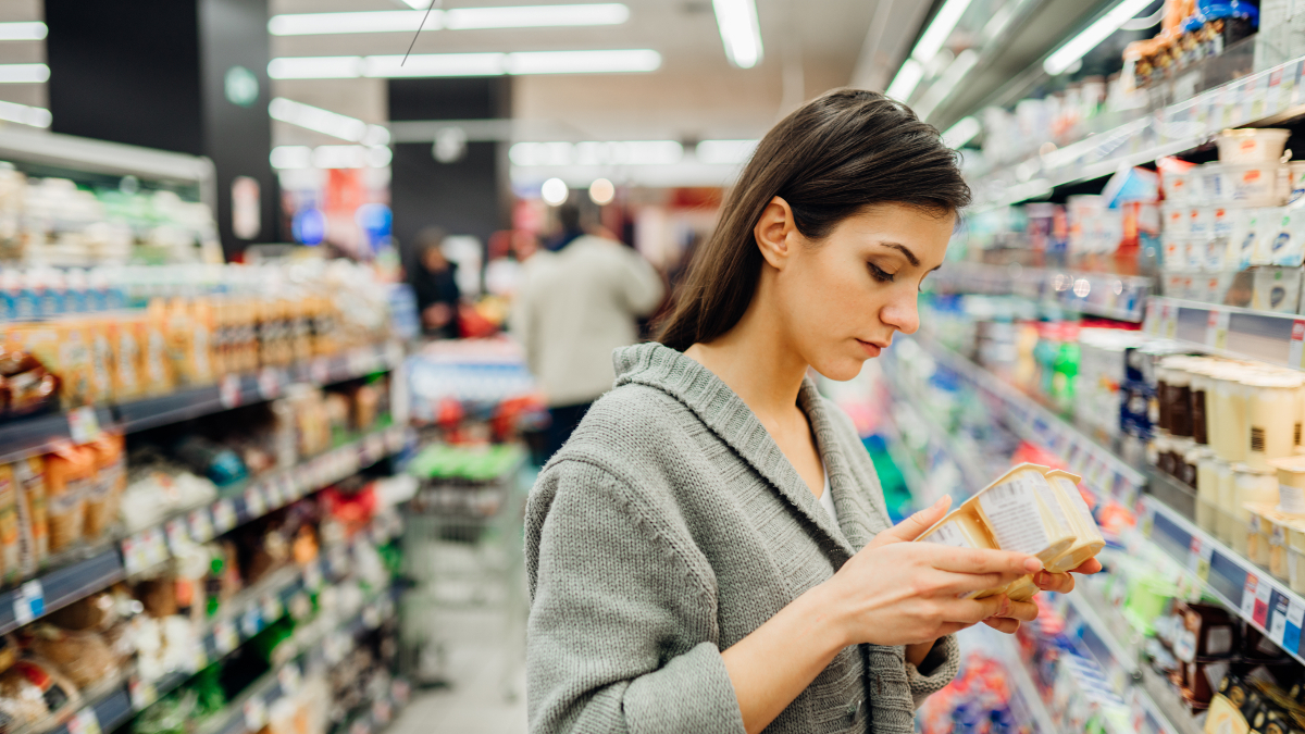 Bleke vrouw die voedingswaarde van een product in de winkel leest