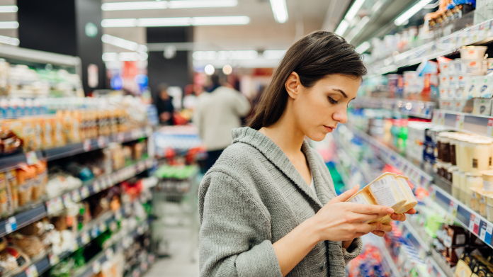 Mujer con anemia que verifica la composición nutricional de un alimento en una tienda