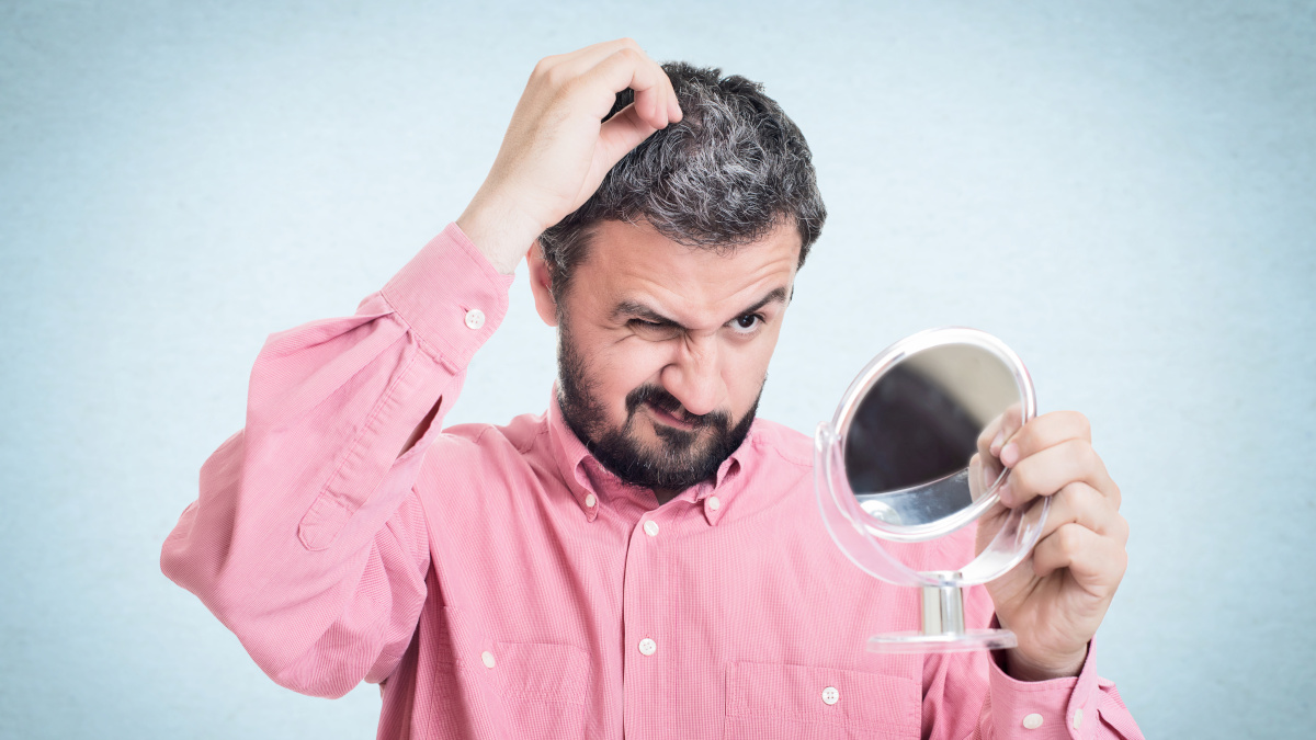 Uomo che vede i suoi capelli diventare bianchi allo specchio