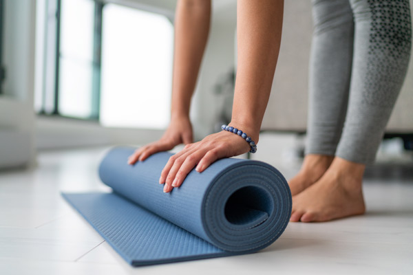 mujer enrollando una esterilla de yoga