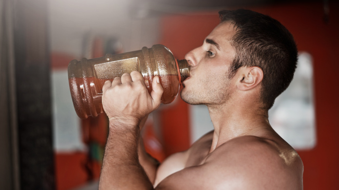 Culturista che beve una bevanda pre-allenamento fatta in casa