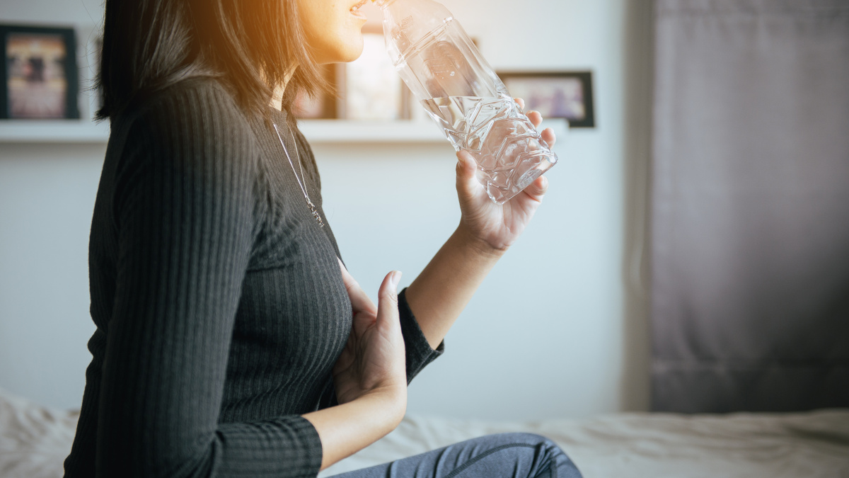 Mulher sentada que sofre de refluxo gástrico com subidas de gases ácidos